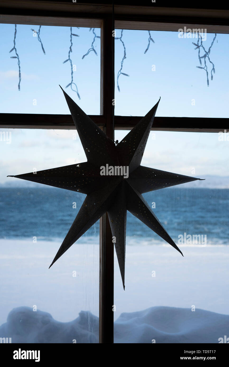 The cardboard seven-pointed star hang on the wooden stick on the window. Stock Photo
