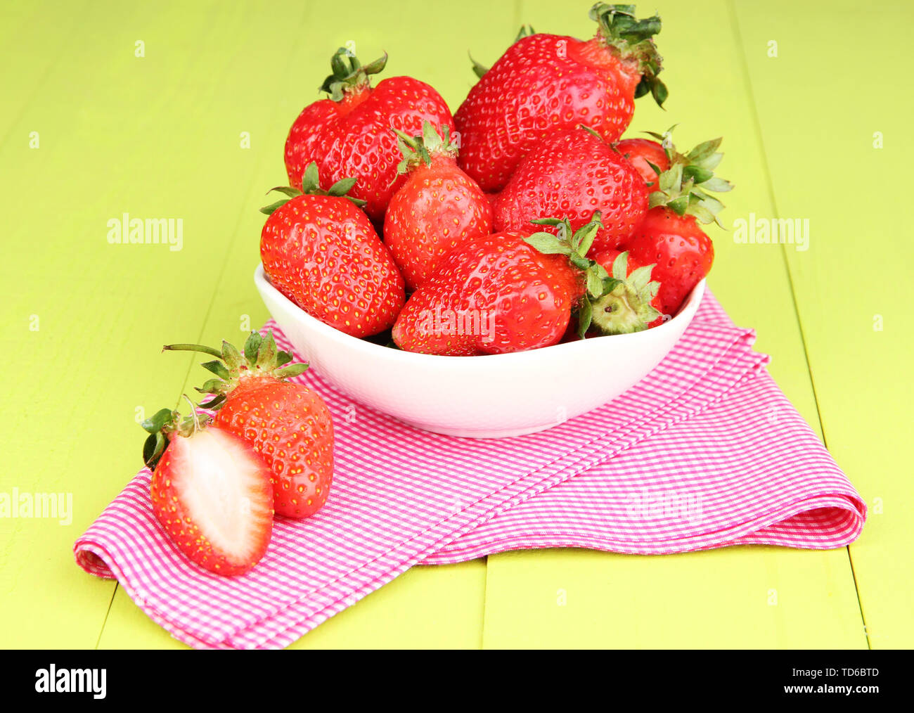 Fresh strawberry in bowl on green wooden background Stock Photo - Alamy