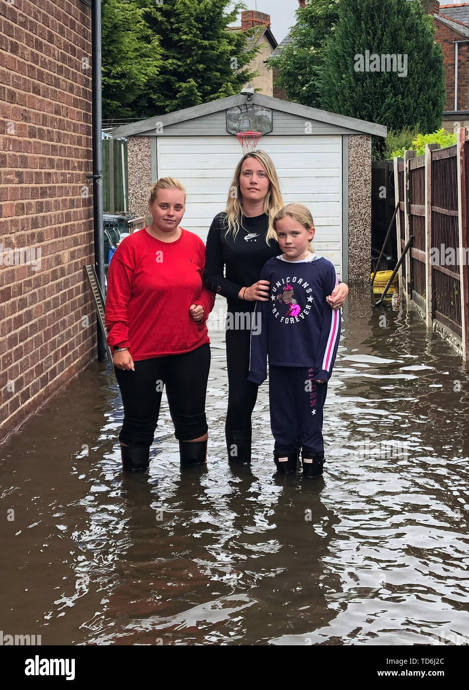 Kelly Holland with daughter Abbi, nine, and sister Nicole Luker in her flood driveway in Hamilton Avenue, Sandycroft, Deeside after heavy rain flooded the area. Stock Photo
