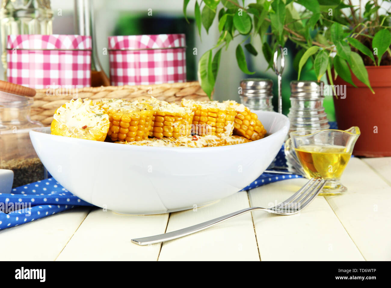 Flavored boiled corn on plate on wooden table on window background