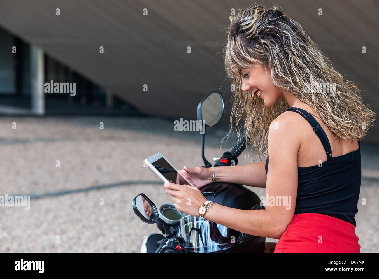 Beautiful young woman using tablet on motorcycle Stock Photo