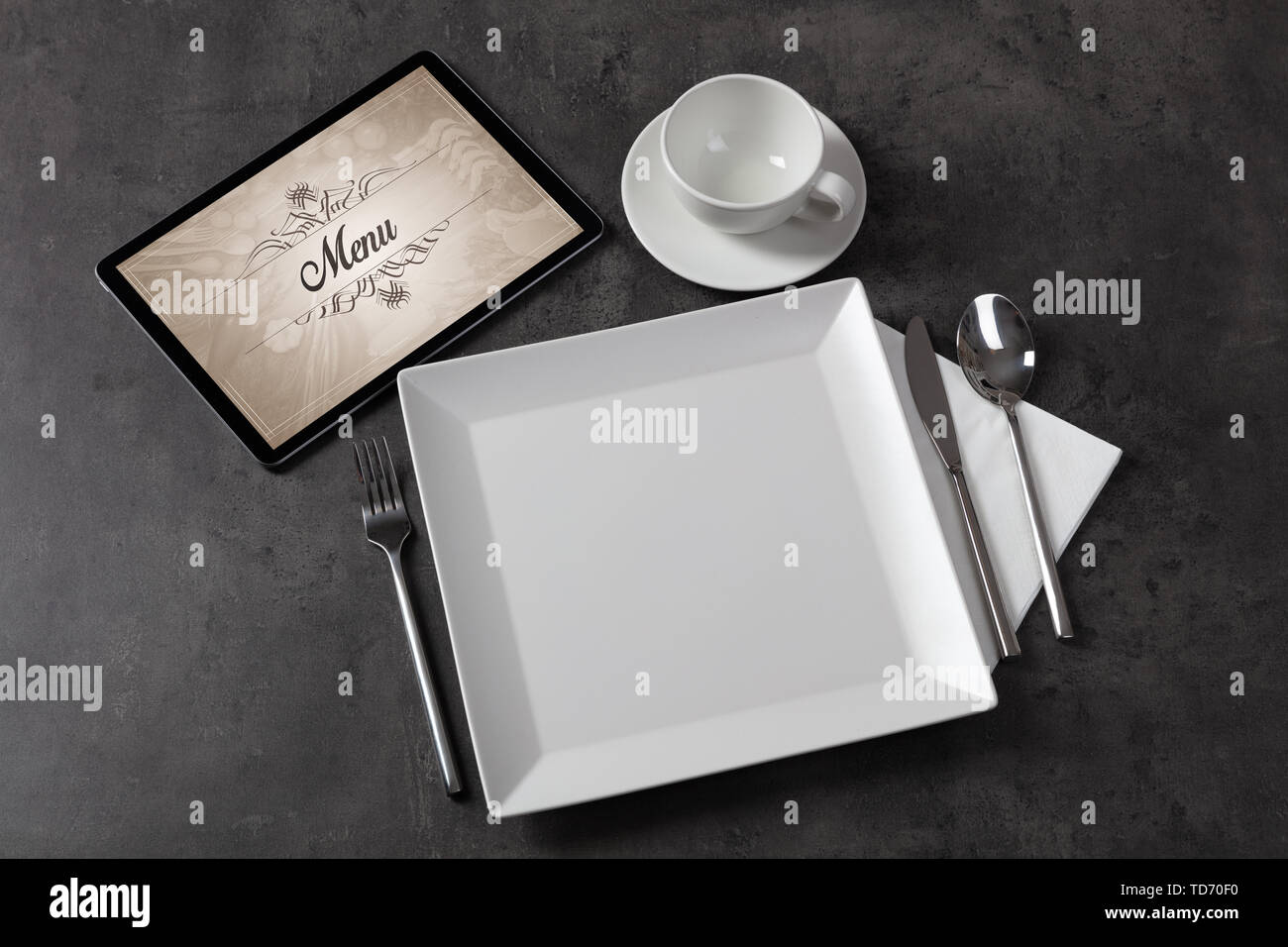 Tablet with stylish restaurant logo and laid table Stock Photo