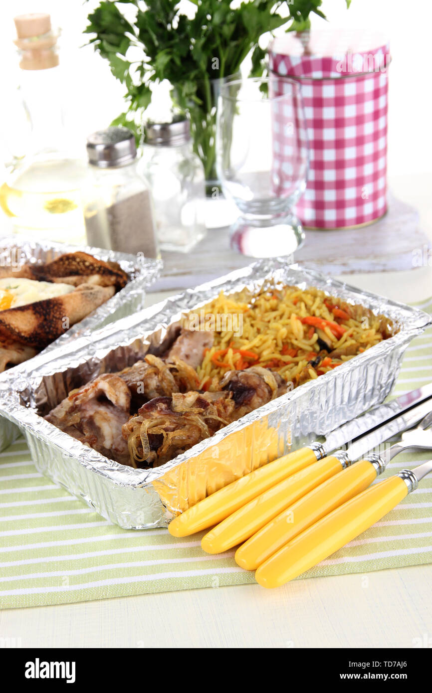 Food in boxes of foil on tablecloth Stock Photo