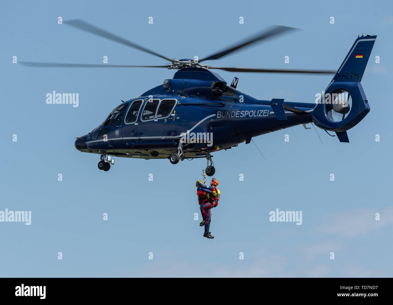 13 June 2019, Saxony, Nünchritz: Air rescue specialists hang on a rope on an EC 155 b1 helicopter during an exercise in helicopter-assisted water rescue from the Elbe. The Bundespolizei-Fliegerstaffel Blumberg, together with the Wasserwacht Sachsen and the Deutsche Lebens-Rettungs-Gesellschaft e.V. (German Life and Rescue Society), leads the (DLRG) is conducting a joint exercise to rescue people from flowing waters. Photo: Robert Michael/dpa-Zentralbild/dpa Stock Photo