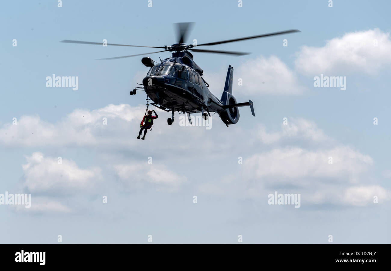13 June 2019, Saxony, Nünchritz: An air rescue specialist hangs from a rope on an EC 155 b1 helicopter during a helicopter-assisted water rescue exercise from the Elbe. The Bundespolizei-Fliegerstaffel Blumberg, together with the Wasserwacht Sachsen and the Deutsche Lebens-Rettungs-Gesellschaft e.V. (German Life and Rescue Society), leads the (DLRG) is conducting a joint exercise to rescue people from flowing waters. Photo: Robert Michael/dpa-Zentralbild/dpa Stock Photo