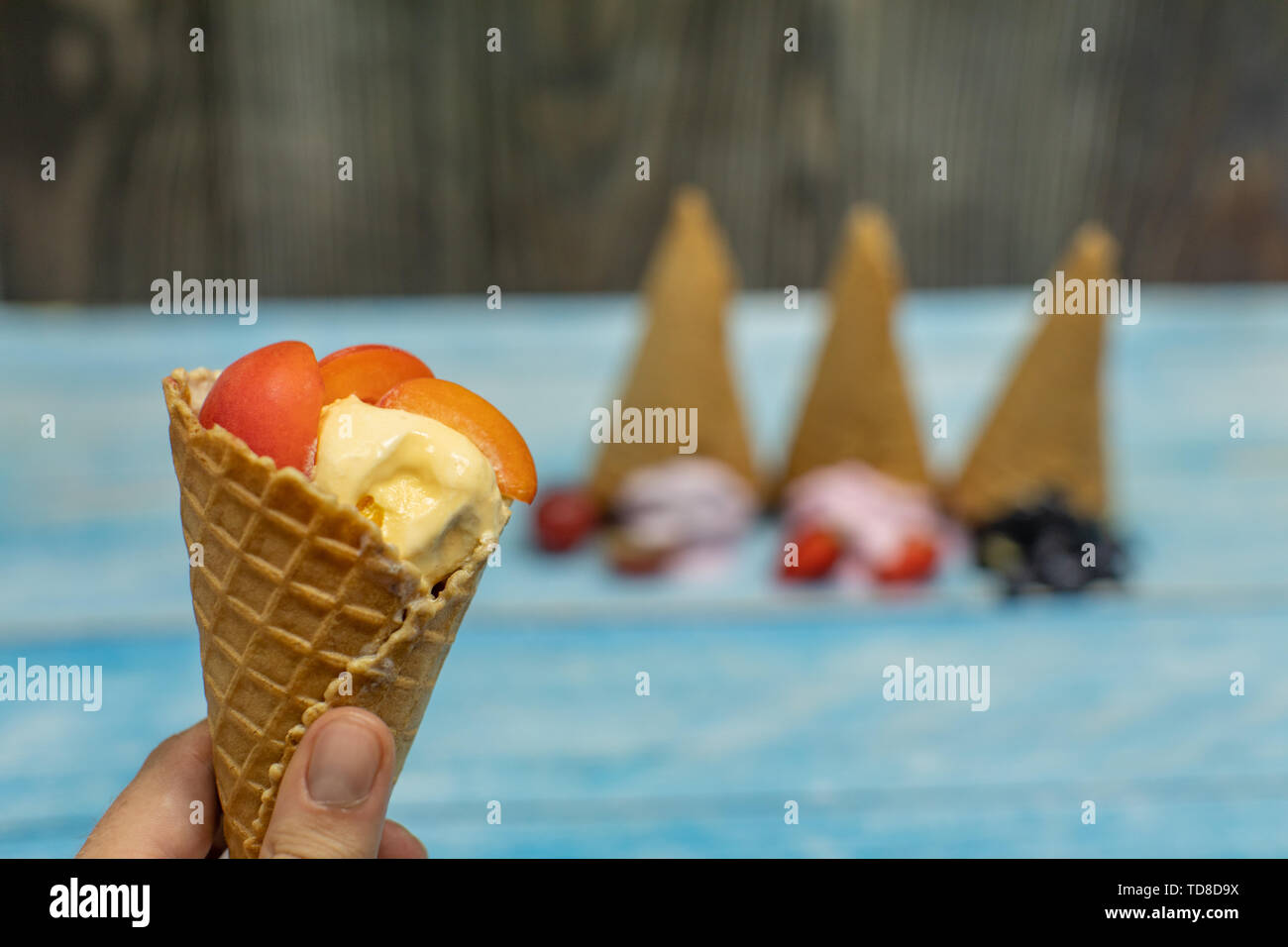 Sweet ice cream in balls on a wooden background. Dessert with different flavors and fresh berries and fruits. Ice cream in a waffle cone. Copy space Stock Photo