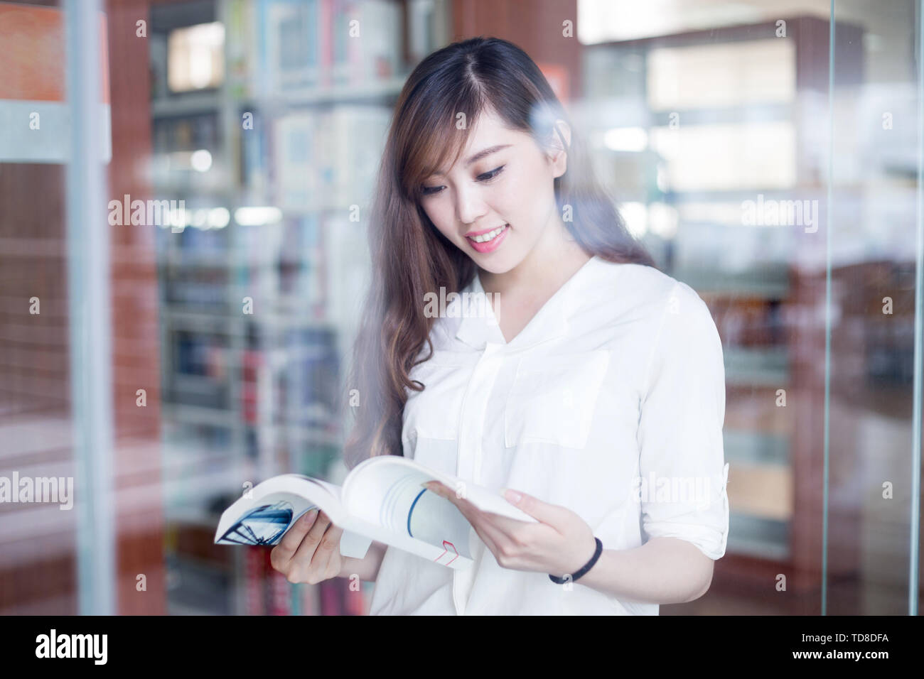 Asian beautiful female student holding book in library Stock Photo - Alamy