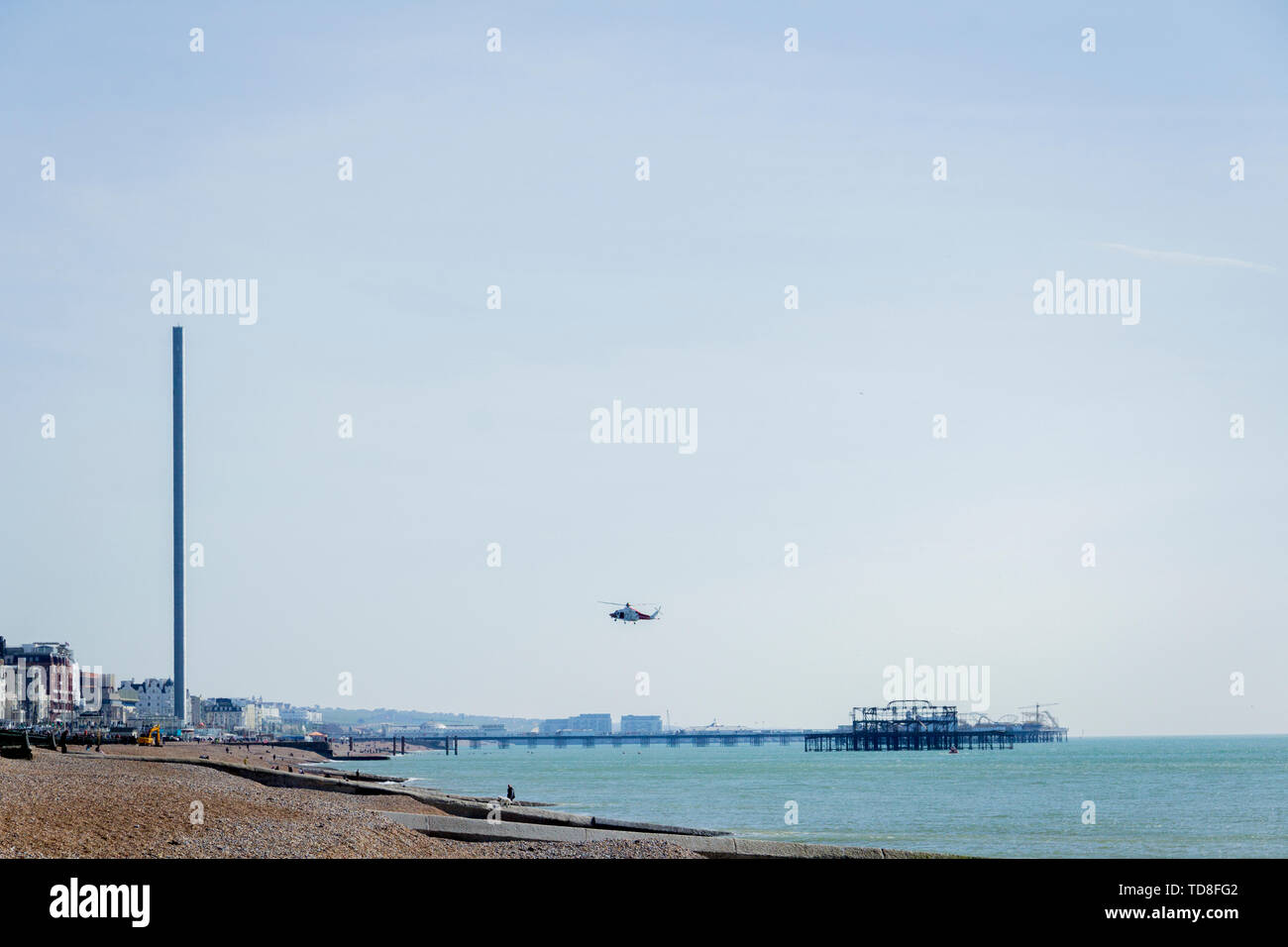 A view of a flying helicopter over the beach in Brighton, Sussex, UK. Brighton Pier, British Airways i360. Stock Photo