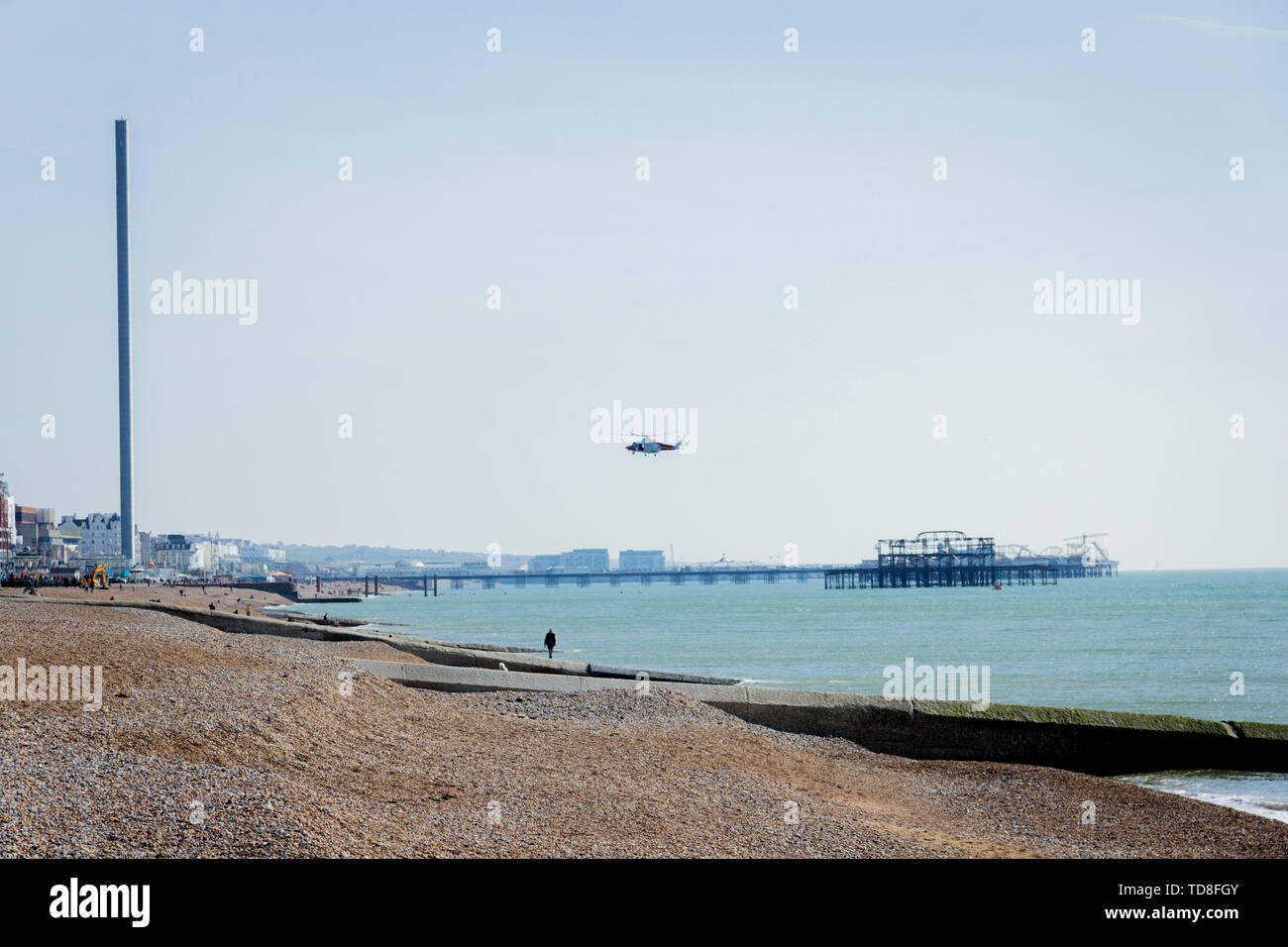 A view of a flying helicopter over the beach in Brighton, Sussex, UK. Brighton Pier, British Airways i360. Stock Photo