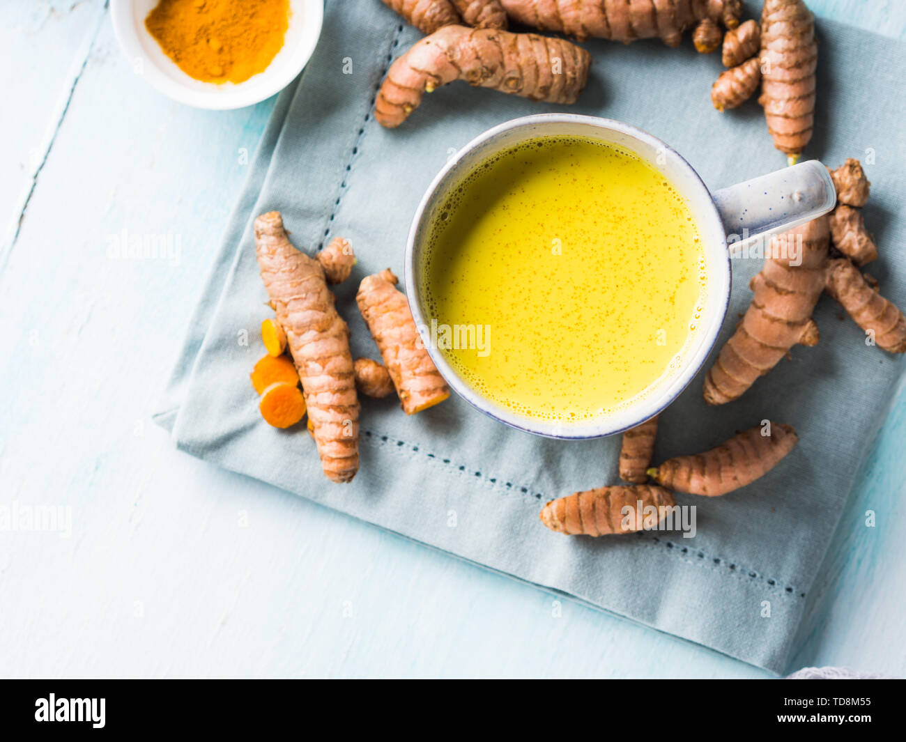 Golden turmeric coconut milk drink in mug on pastel background. Healthy