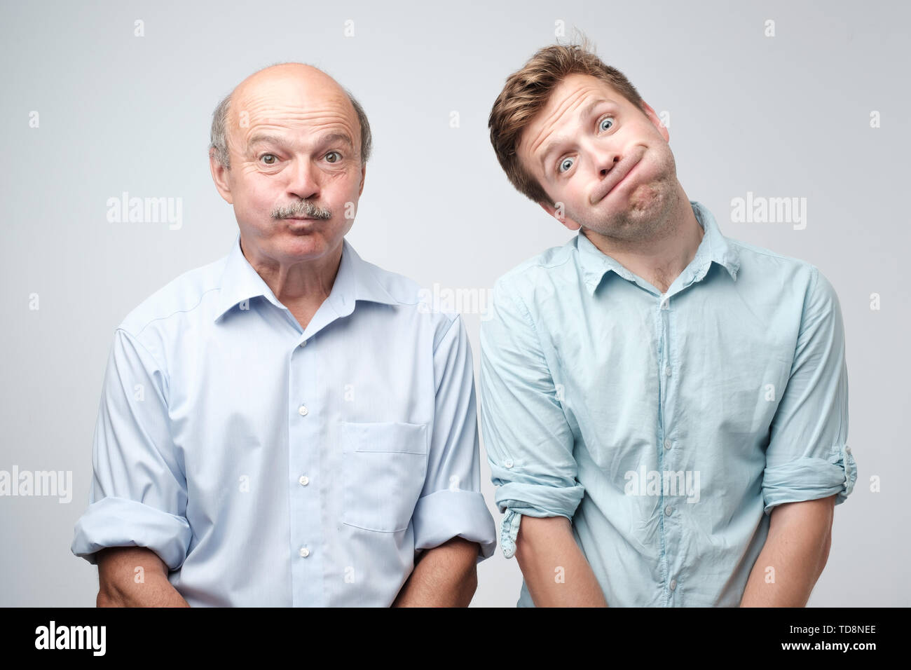 Two men grimacing, inflating cheeks, holding breath Stock Photo
