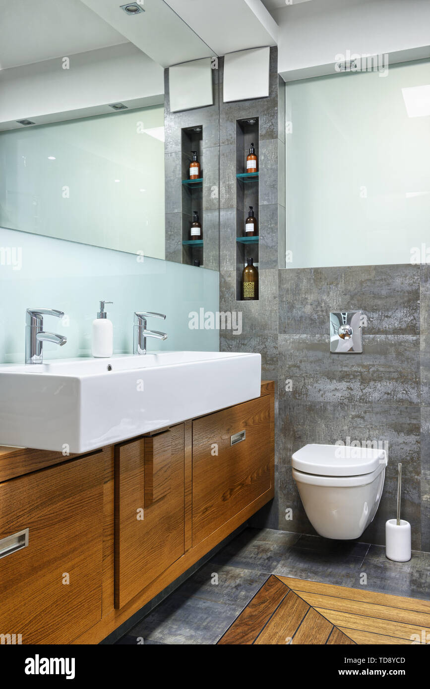 Glass shelves next to wall mirror and large double washbasin in modern ...