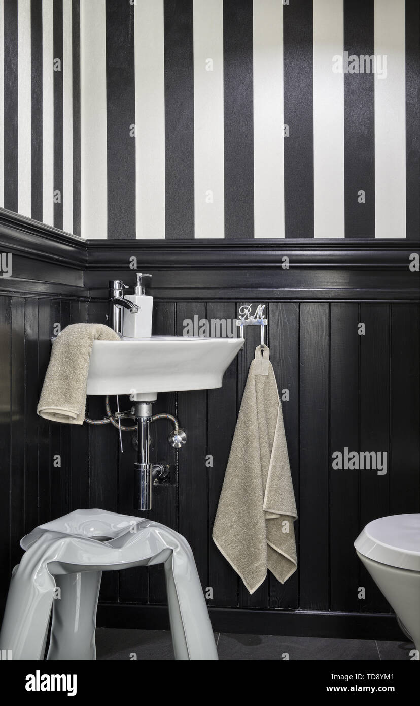 Metal stool in small restroom with wall panelling and black and white  stripes wallpaper UK  IRISH USE ONLY Stock Photo  Alamy