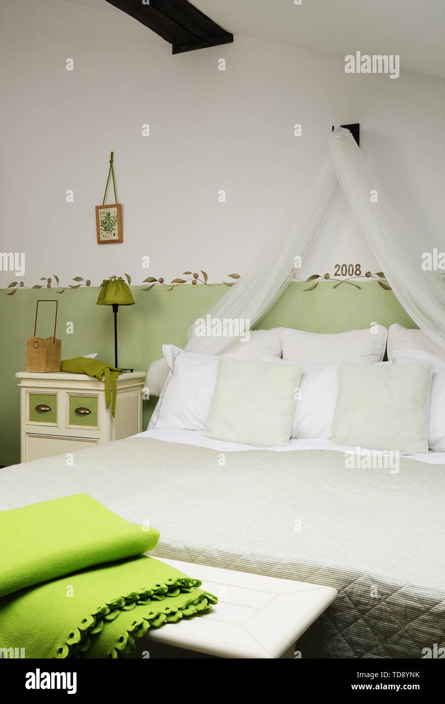 Green Folded Blanket On Bench In Front Of Comfortable Double Bed