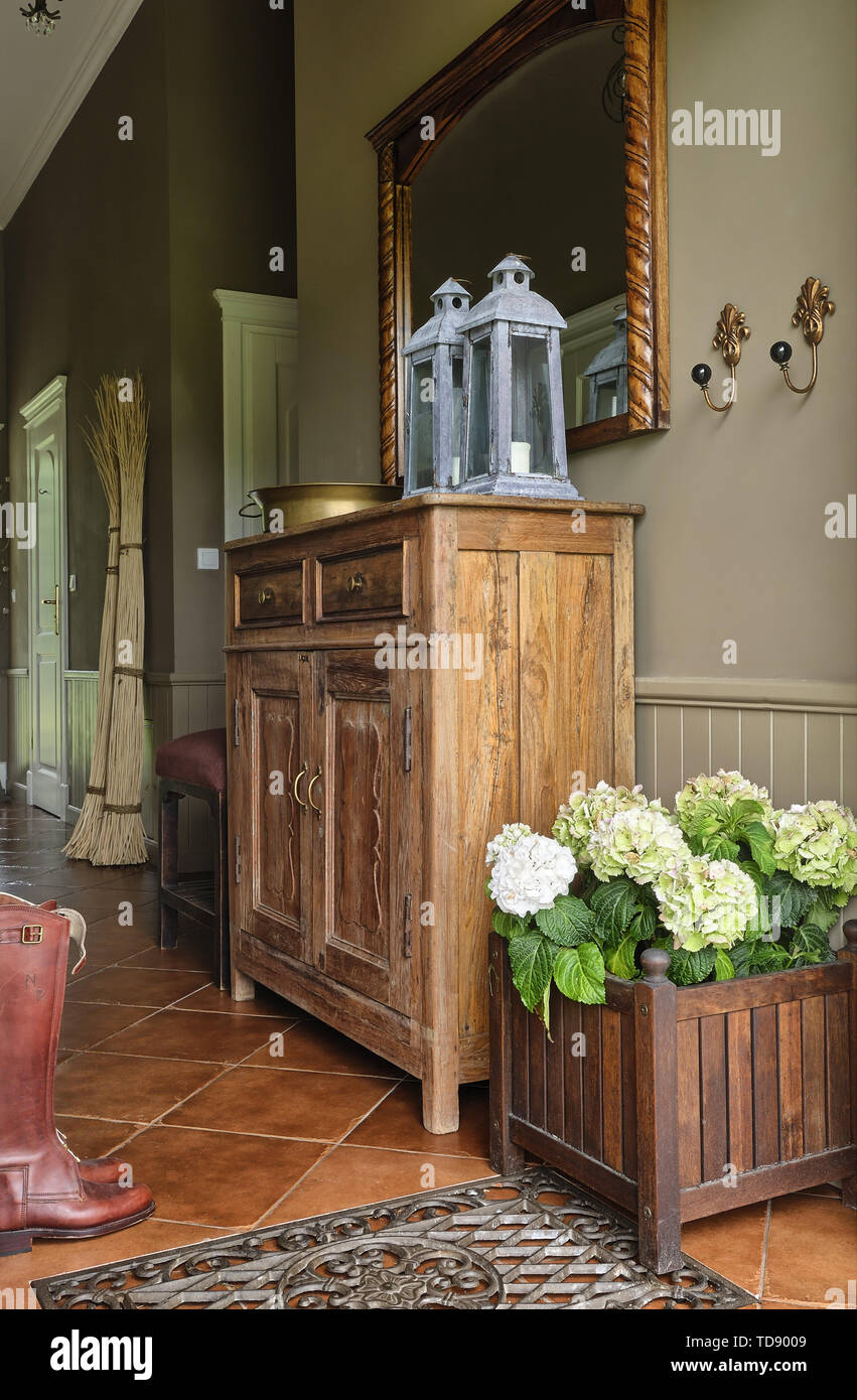 Hydrangea flowers in wooden box next to wooden cupboard in country style hallway   UK AND IRISH RIGHTS ONLY Stock Photo