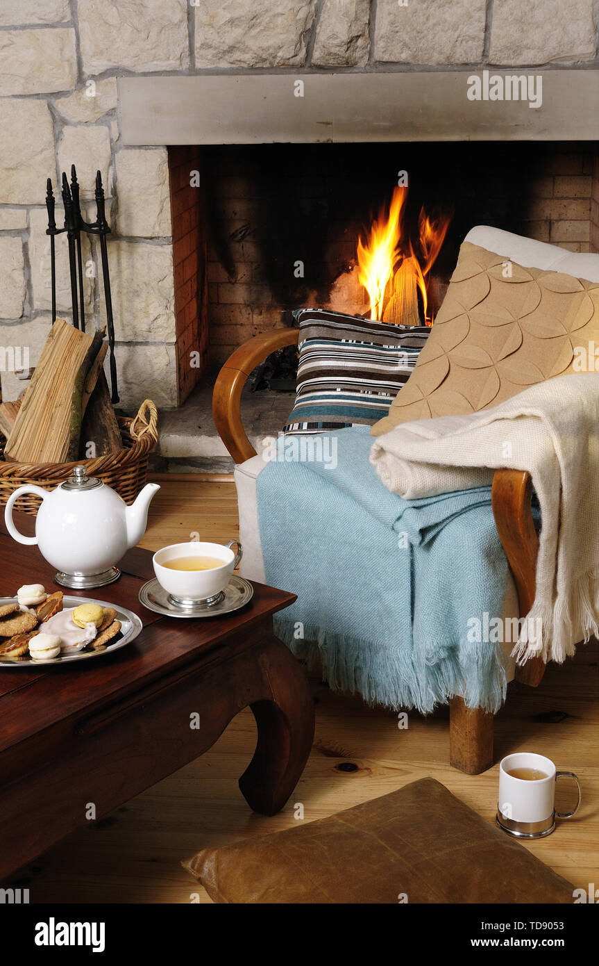 Teapot And Biscuits On Coffee Table With Chair In Front Of Fireplace With Lit Fire Uk And Irish Rights Only Stock Photo Alamy
