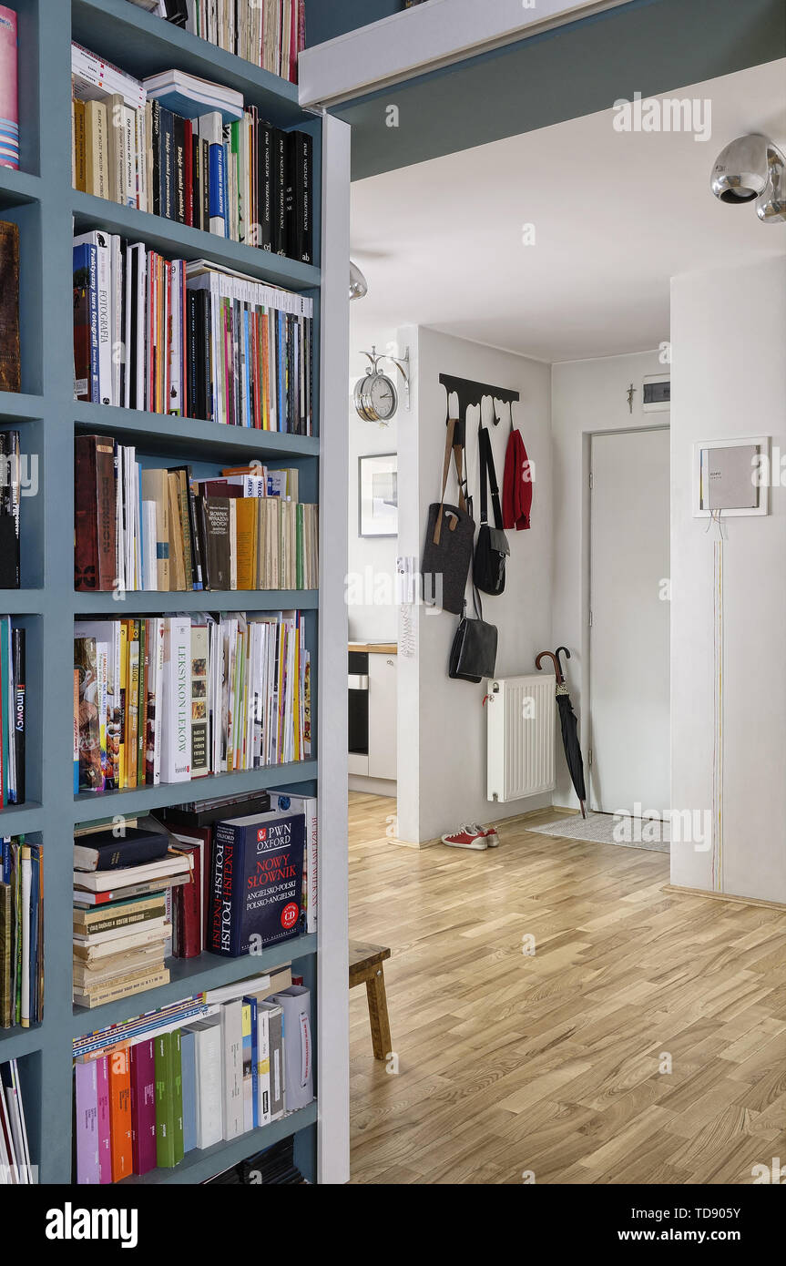 Bookcase in hallway next to apartment entrance with leather handbags on