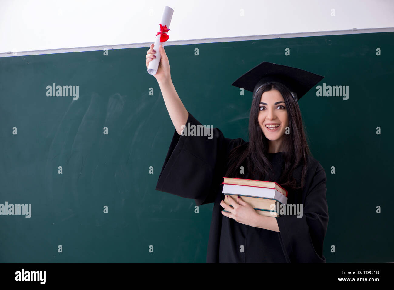 Female graduate student in front of green board Stock Photo - Alamy