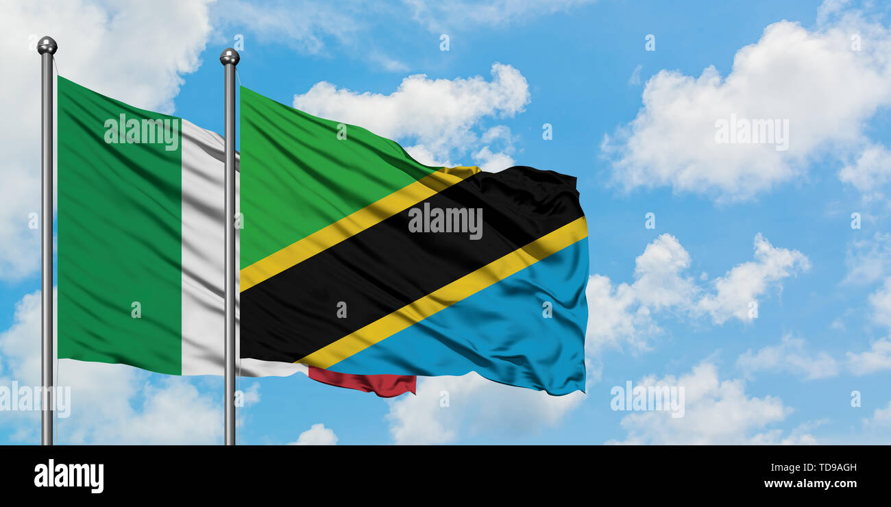 Italy and Tanzania flag waving in the wind against white cloudy blue ...