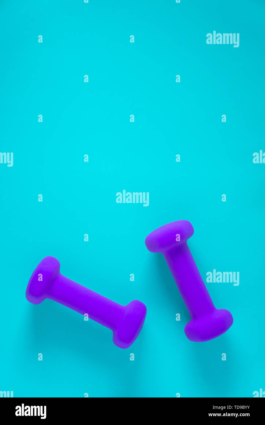 Fitness equipment with womens purple weights/ dumbbells isolated on a light sky blue background with copyspace (aka empty text space). Stock Photo