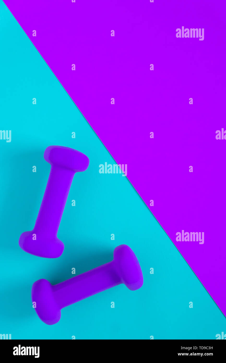 Fitness equipment with womens purple weights/ dumbbells isolated on a light sky blue and purple background with copyspace (aka empty text space). Stock Photo