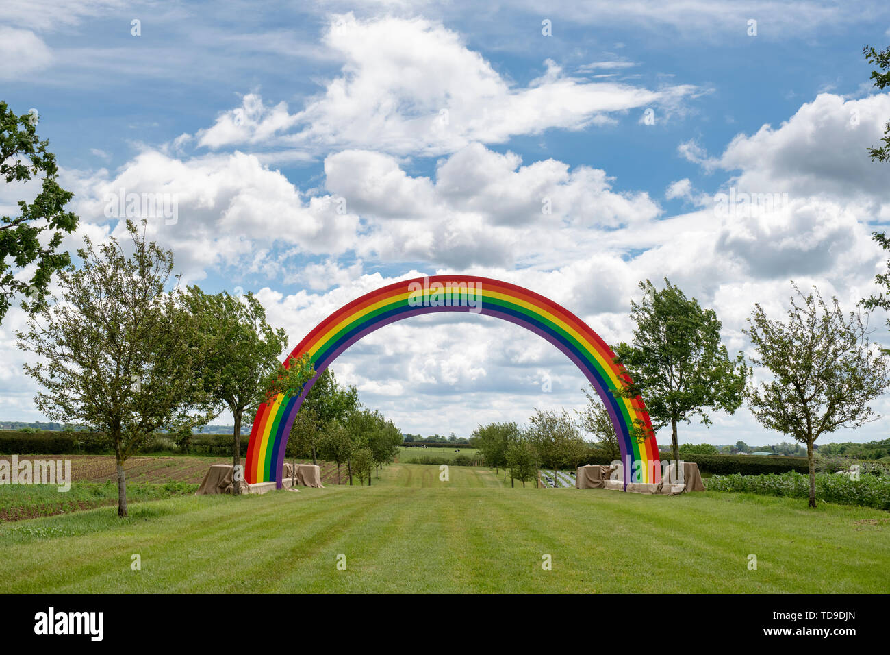 Large rainbow spanning a field at Daylesford Organic farm summer festival. Daylesford, Cotswolds, Gloucestershire, England Stock Photo