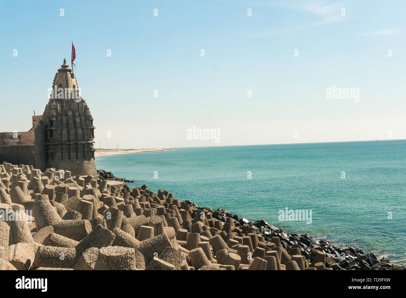 Lone hindu temple with flag on arabian sea coast with wave breakers Stock Photo