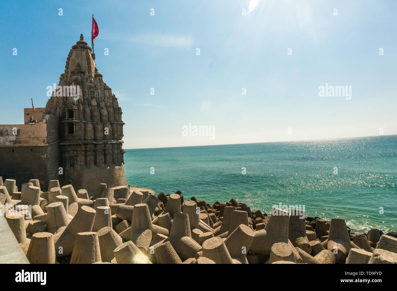 Lone hindu temple with flag on arabian sea coast with wave breakers Stock Photo