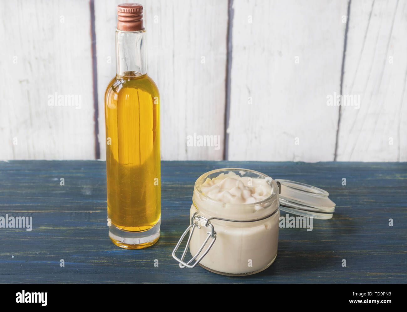 Homemade facial cream of argan oil, in a glass jar with bottle of oil to the side, on a wooden background Stock Photo