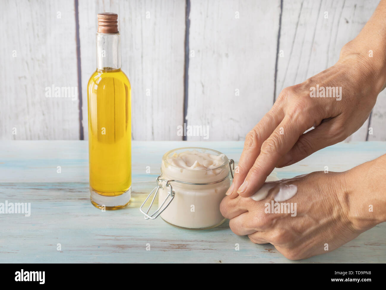 Human hands cracked spreading argan cream. Cream for cracked argan hands in a glass jar. Bottle with argan oil Stock Photo