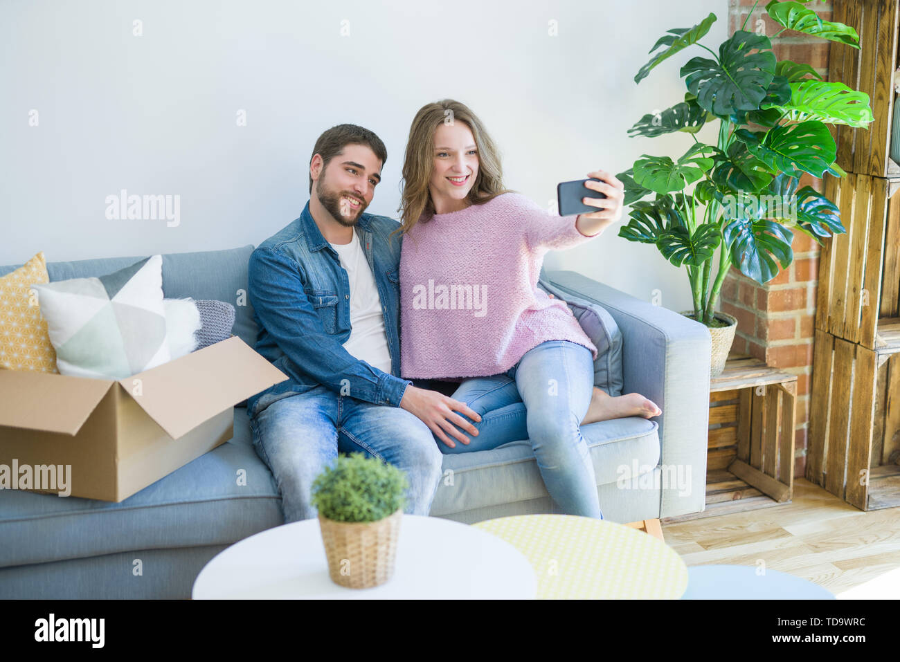 Young beautiful couple taking a selfie photo using smartphone sitting ...