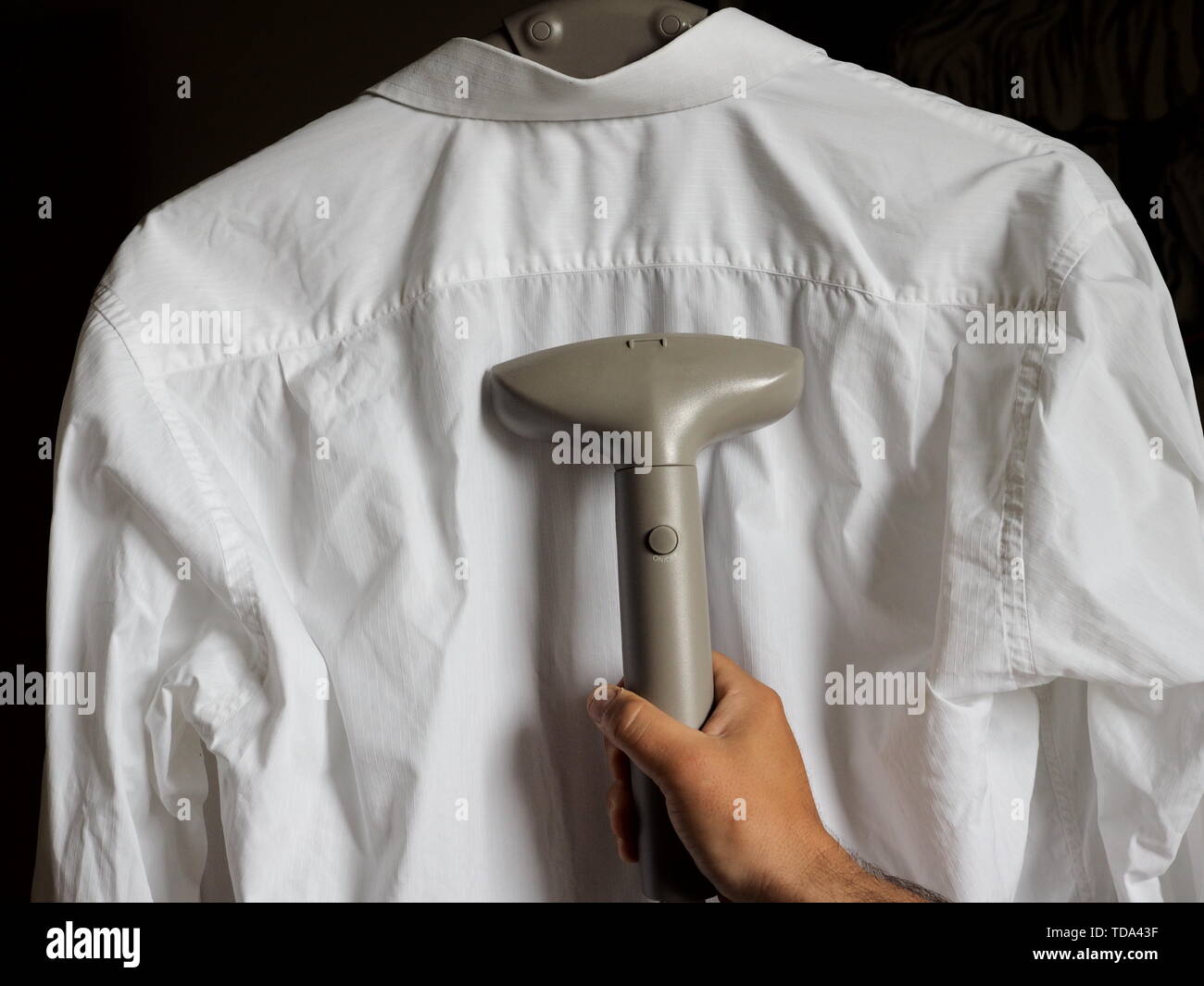 Man ironing shirt with garment steamer Stock Photo