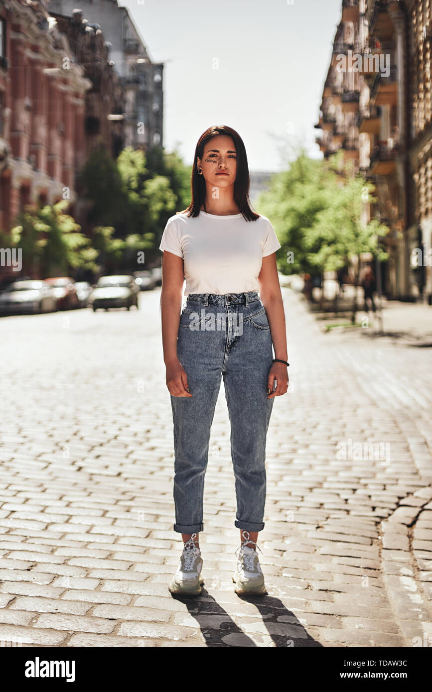 Feeling strong. Vertical photo of young woman in casual clothes standing on the road and looking at camera. Protest concept. Active youth Stock Photo