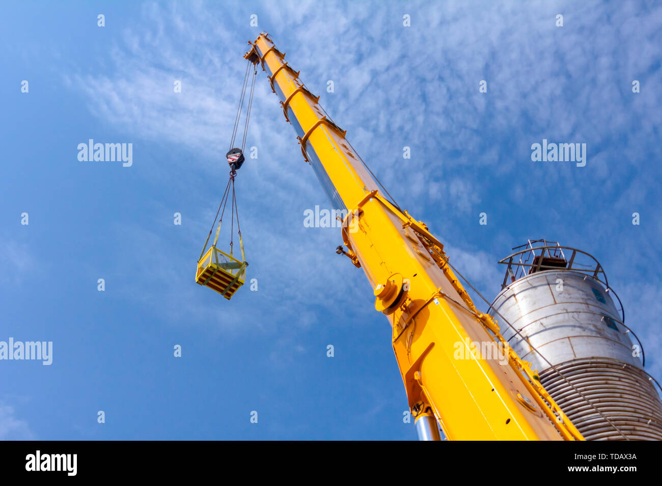 Mobile crane with hook and straps is raising work platform, basket