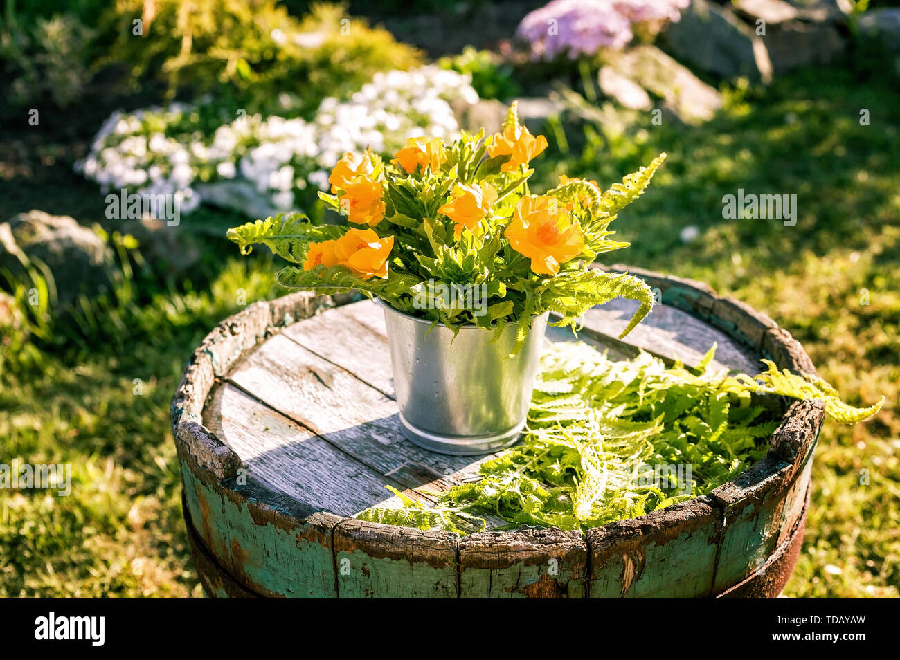 Bouquet of flowers in tin pots on an old wooden barrel. Wedding outdoor floristics Stock Photo