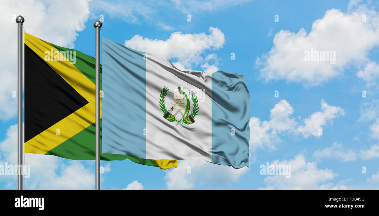 Jamaica and Guatemala flag waving in the wind against white cloudy blue sky together. Diplomacy concept, international relations. Stock Photo