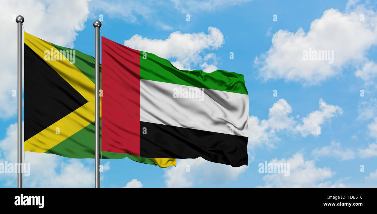 Jamaica and United Arab Emirates flag waving in the wind against white cloudy blue sky together