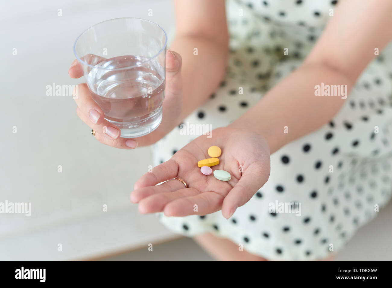 Woman with pills and glass of water indoors Stock Photo