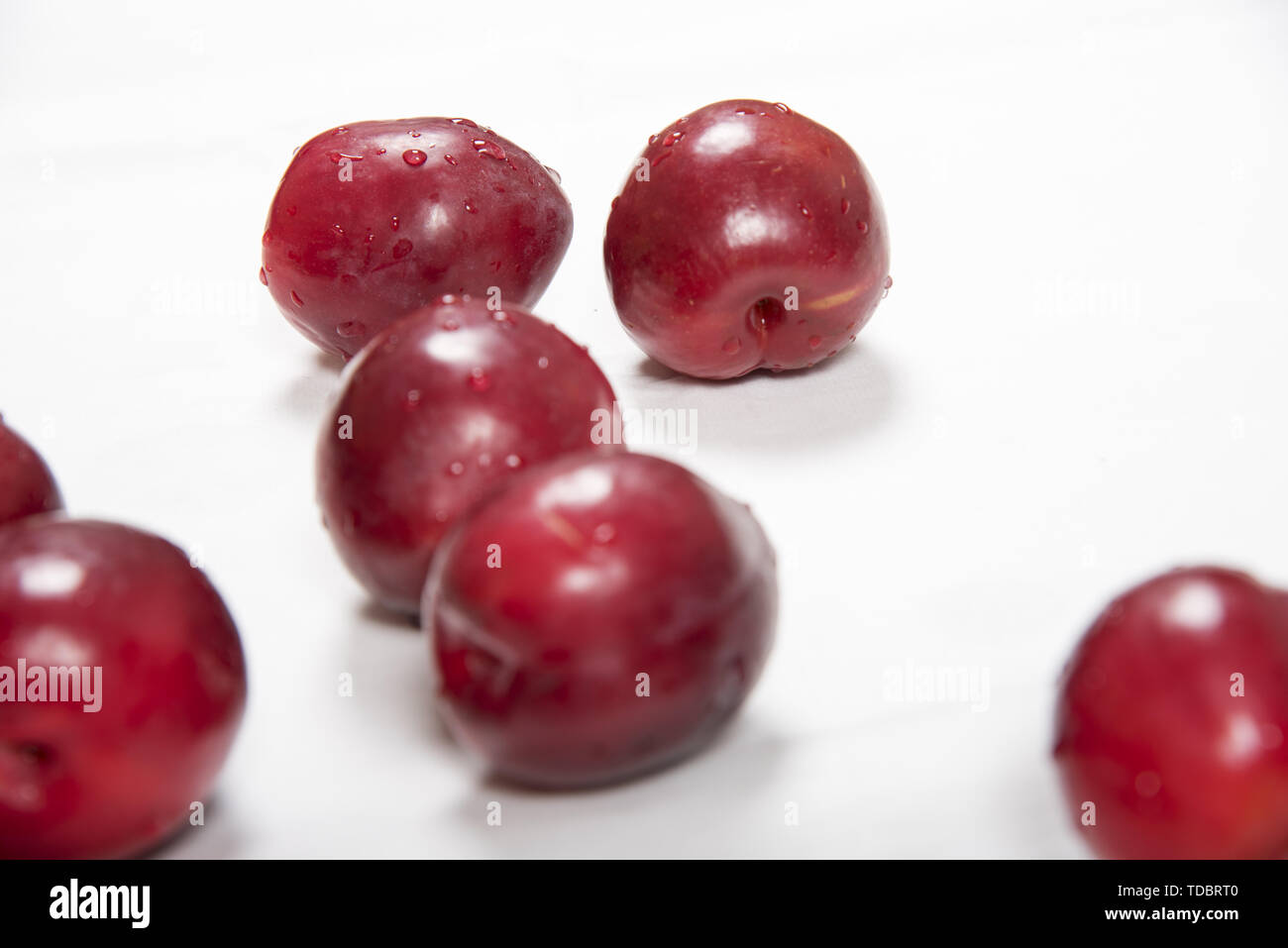 Casually laid red plum fruit on white background Stock Photo