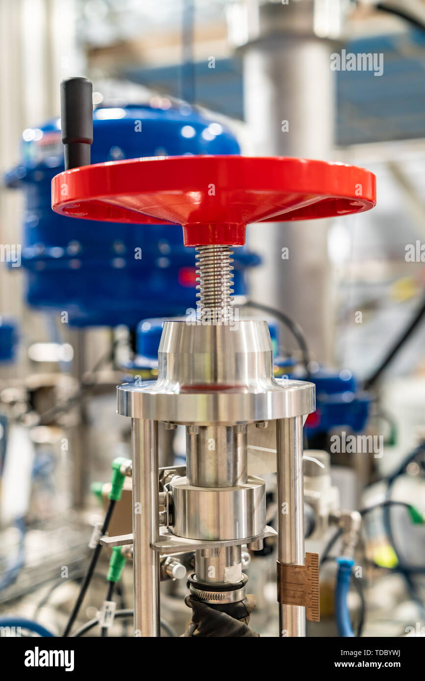 Red manual hand valve in a in a large industrial plant Stock Photo