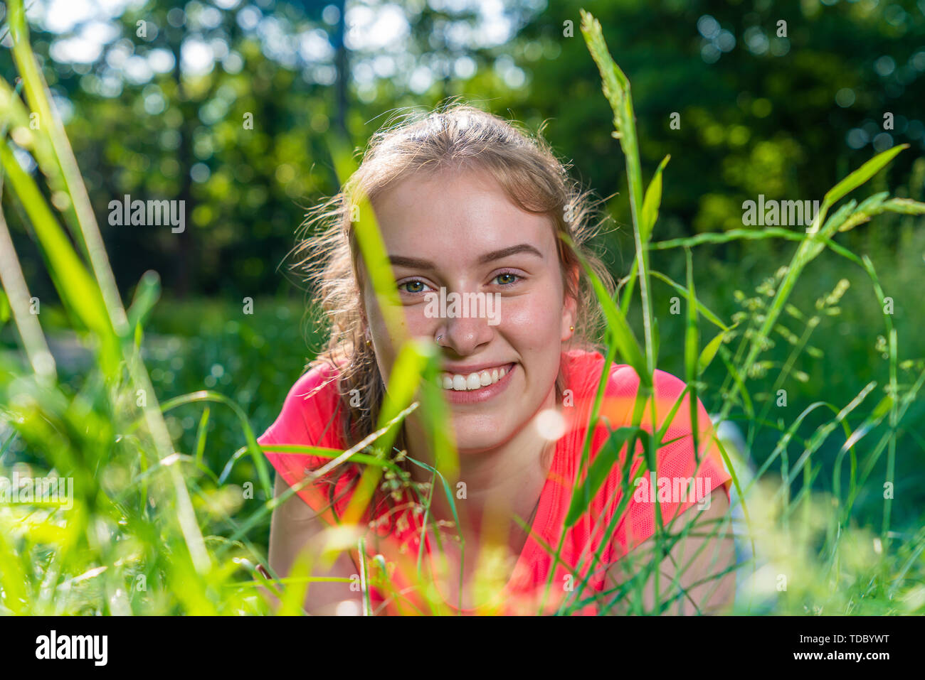 young woman lies smiling in a meadow and looks into the camera Stock Photo