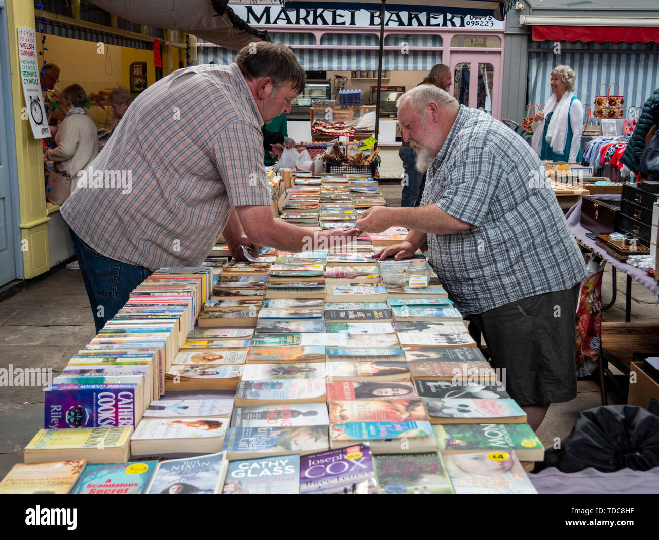 Shoppers browse on secondhand book stall in the Abergavenny indoor market hall Wales UK Stock Photo