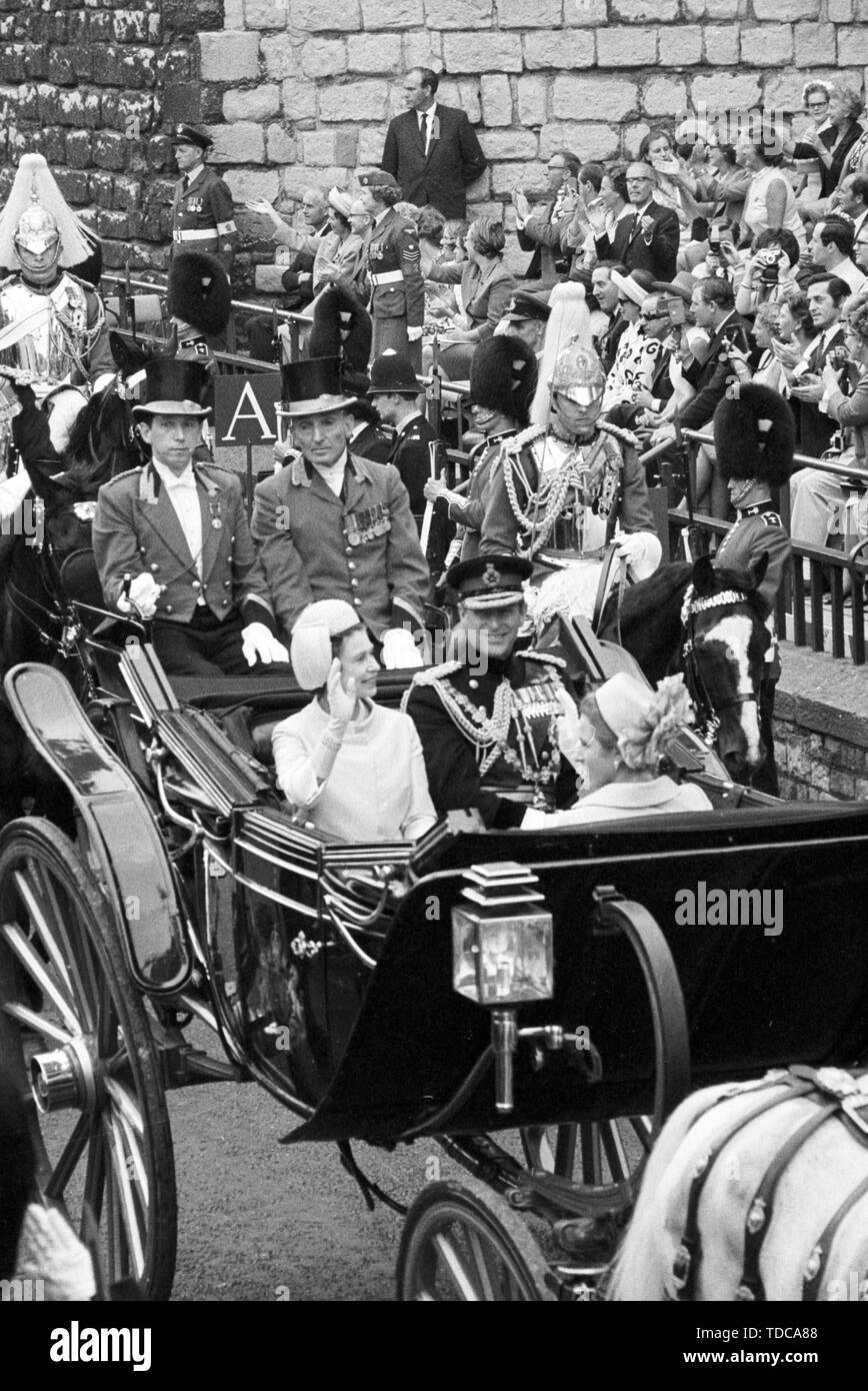 Queen Elizabeth II waves from the open carriage as she drives with Prince Philip, Duke of Edinburgh and Princess Anne past the King's Gate of Caernarfon Castle to the investiture of the Prince of Wales. Stock Photo