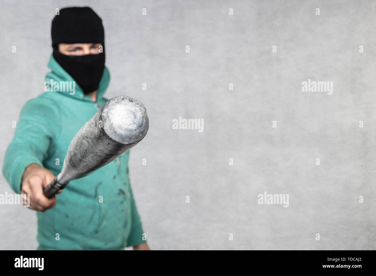 a masked hooligan holds a baseball bat in his hand Stock Photo - Alamy