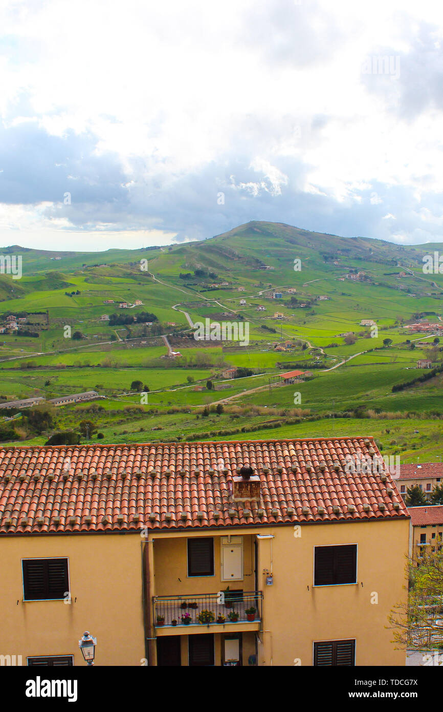 Vertical photo capturing amazing Sicilian landscape with houses in village Gangi in Italy. Cloudy day. Green hilly countryside. Popular tourist destination. Stock Photo