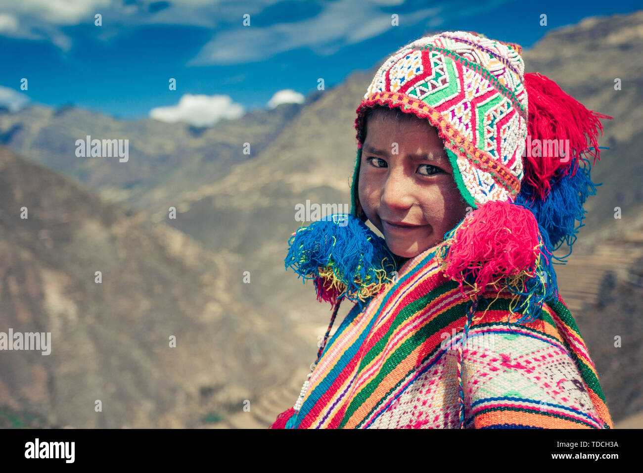 Cusco / Peru - May 29.2008: Portrait of a  boy smiling, dressed up in colorful native peruvian costume standing on the hill in the mountains. Stock Photo