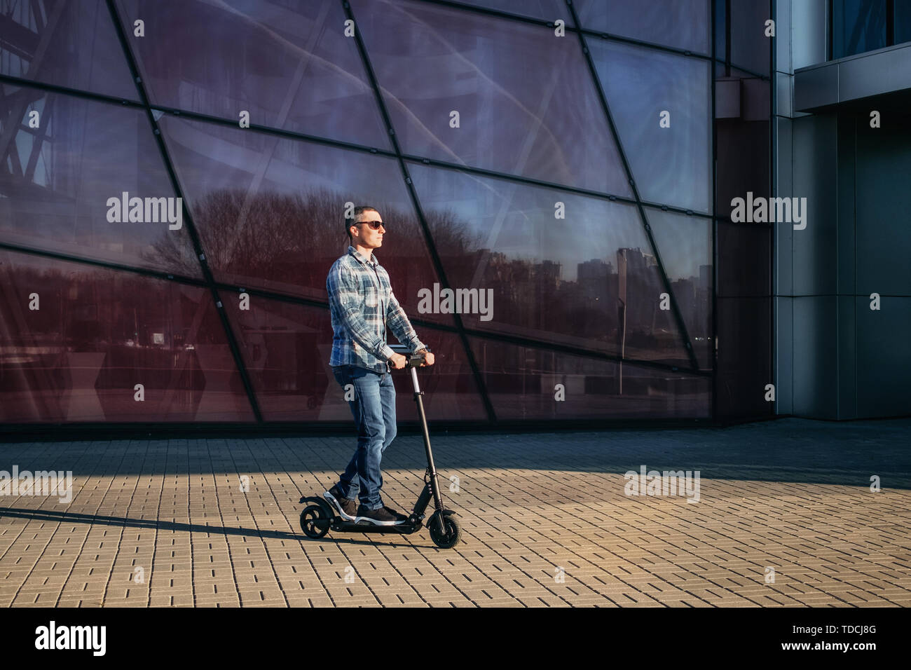 Adult riding scooter on pavement hires stock photography and images
