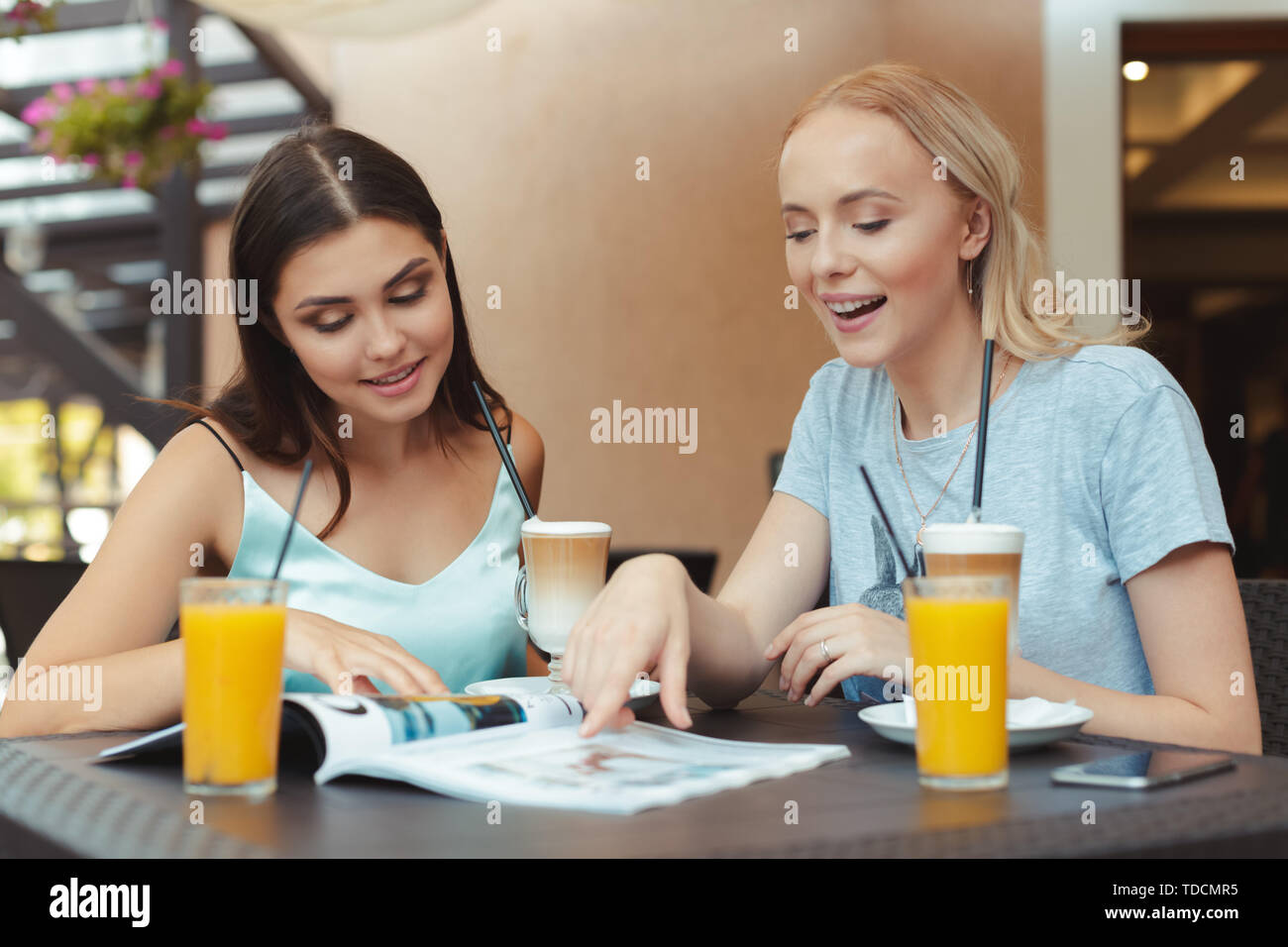 Two beautiful young girls sitting by the table in cafe Stock Photo - Alamy