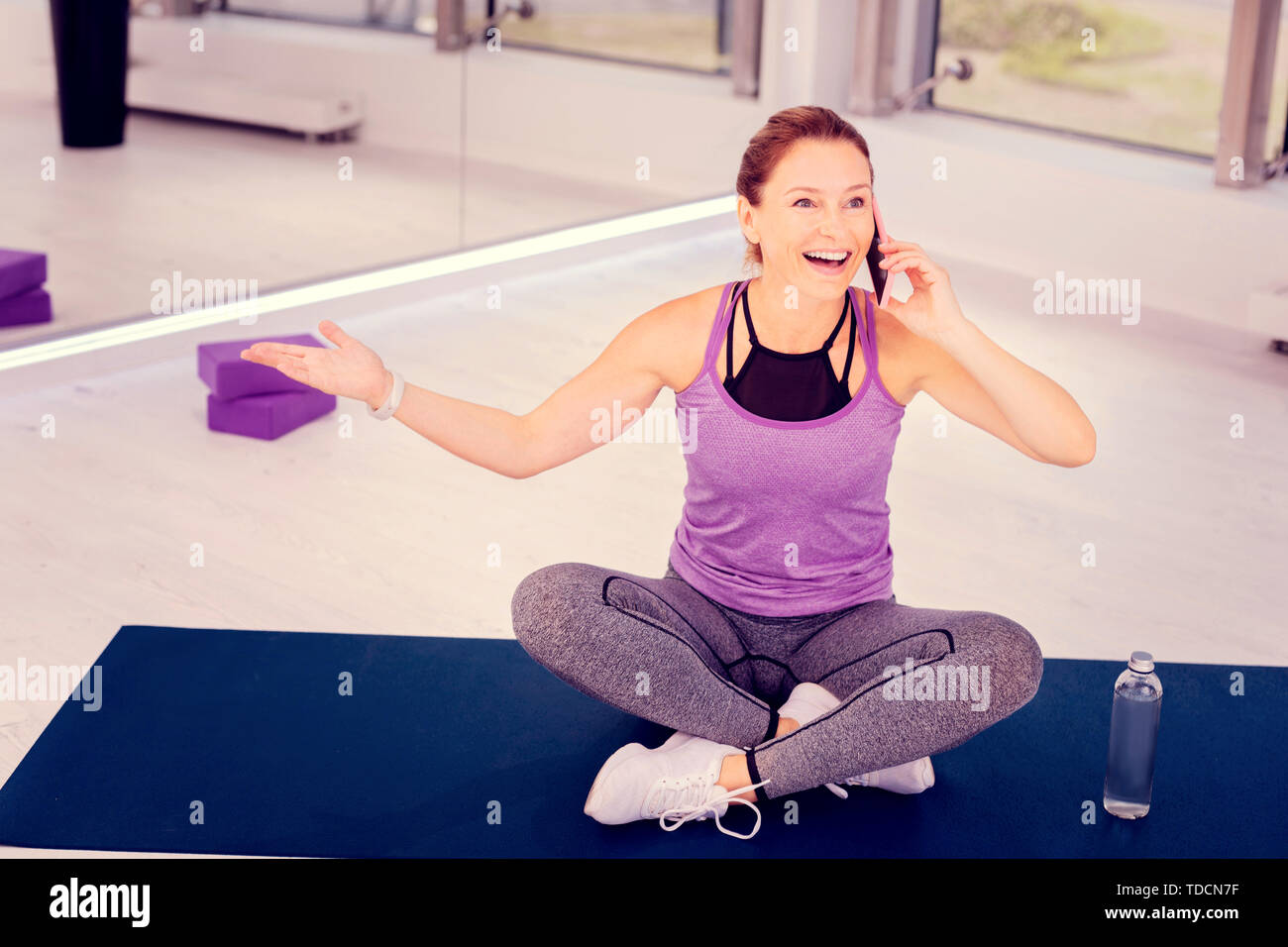 Emotional female person sitting on yoga mat Stock Photo - Alamy