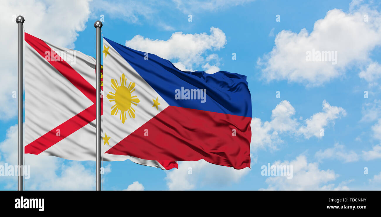 Jersey and Philippines flag waving in the wind against white cloudy blue sky together. Diplomacy concept, international relations. Stock Photo